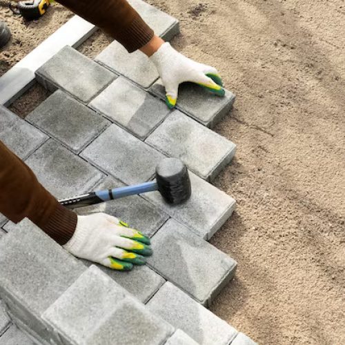 hands-worker-installing-concrete-blocks-paving-slabs-with-rubber-hammer_199620-11735